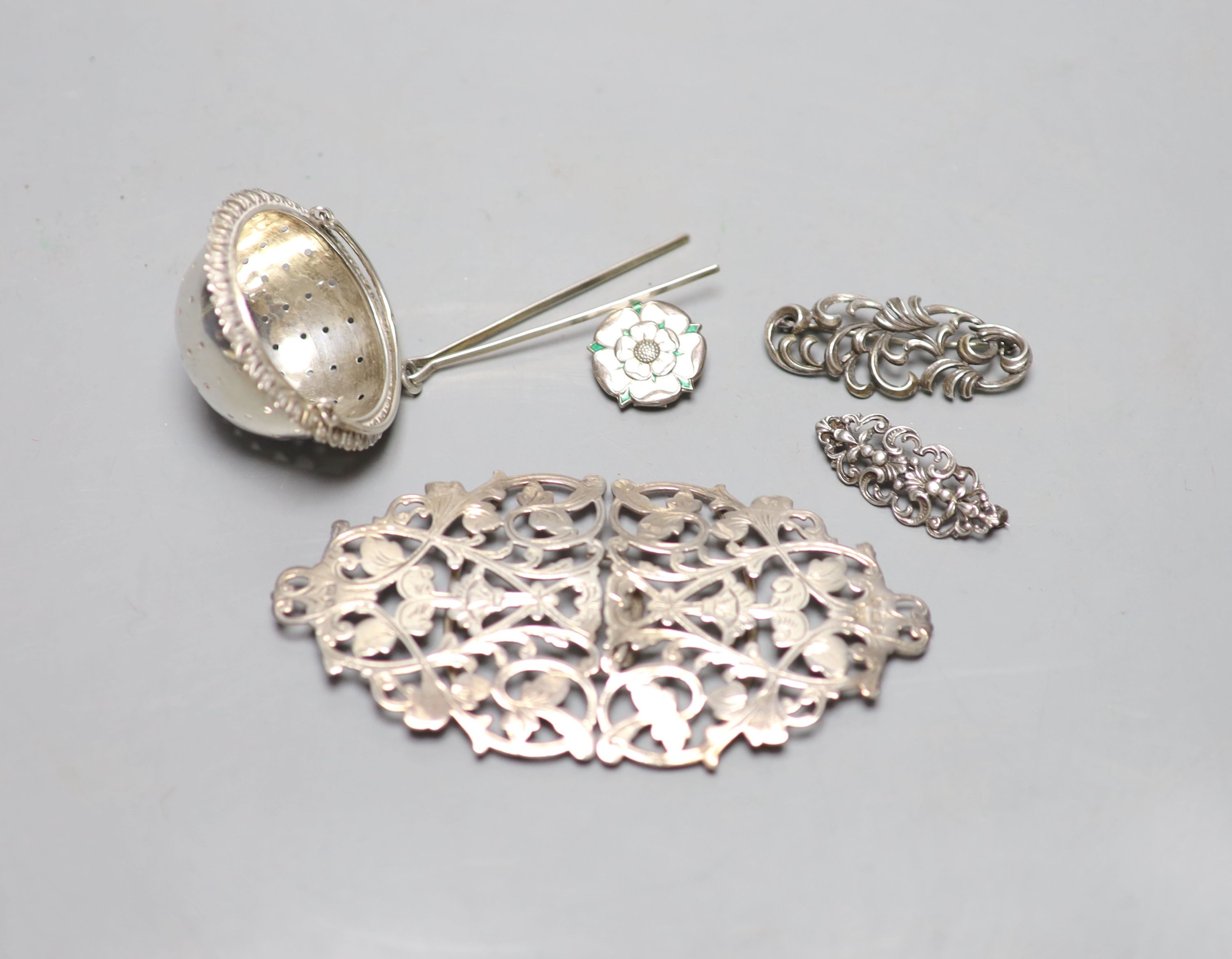 An Edwardian pierced silver belt buckle, Birmingham, 1901, 11.2cm, two brooches , rose brooch and a tea strainer.